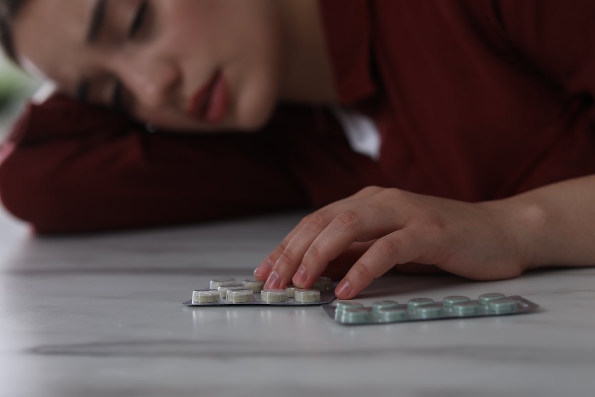 Woman feeling depressed leaning on a table with antidepressant pills